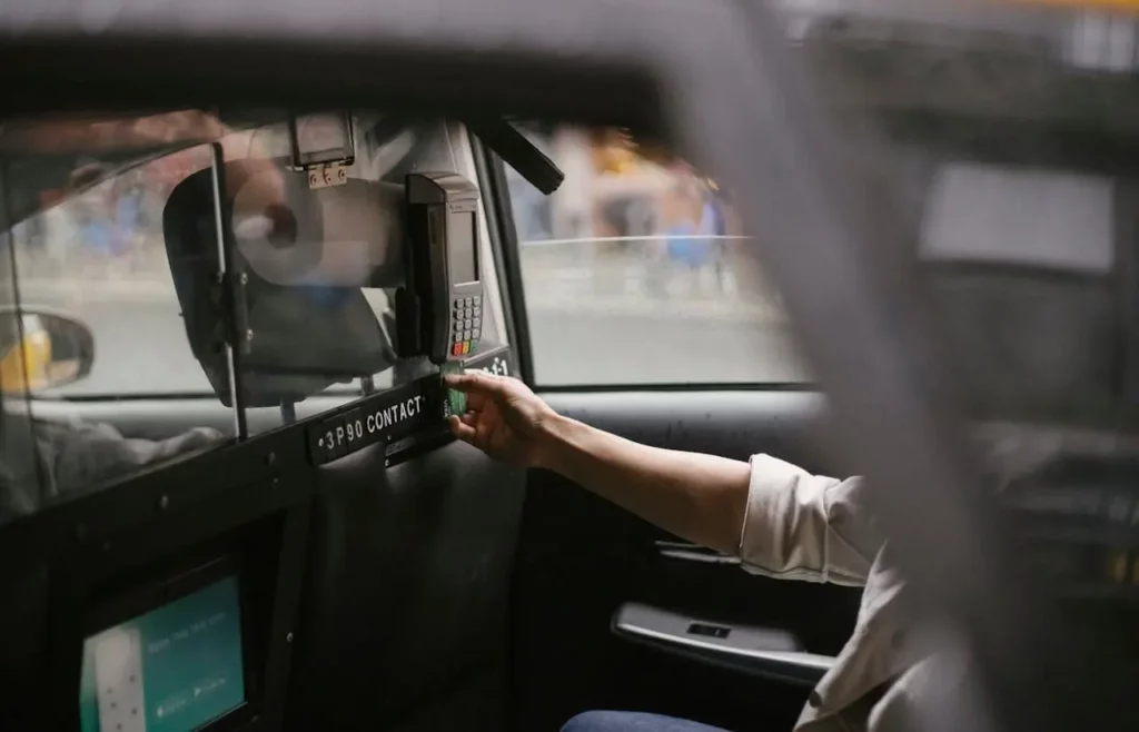 a taxi passenger paying for fare by swiping his credit card over a card reader
