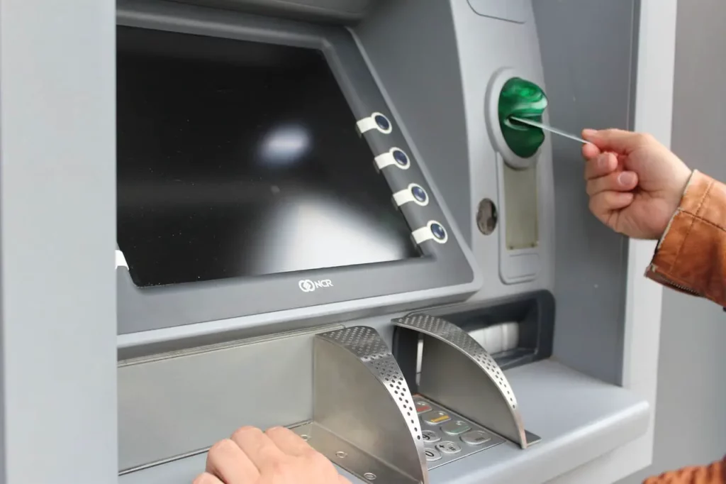someoune is using an atm and inserting the card in the atm card slot