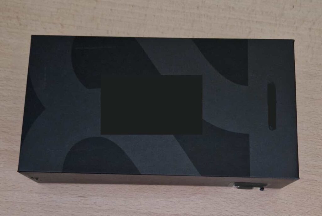 an original black packaging of a smartphone, with the logo and model censored.